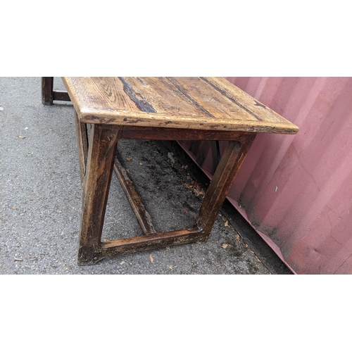 148 - An 18th century vernacular oak dining table, having a plank constructed top, four chamfered legs uni... 