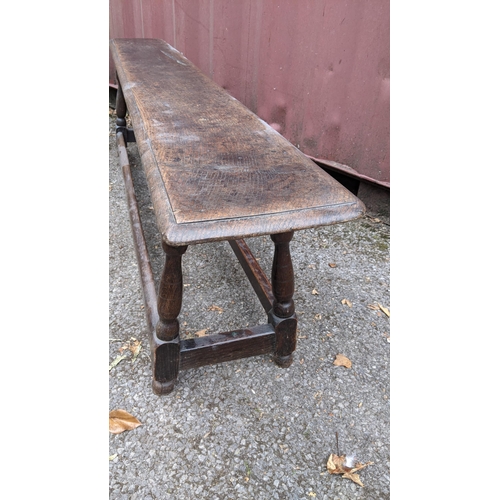 167 - An 18th century oak bench, having a single plank top, above four knop turned columns, united by stre... 