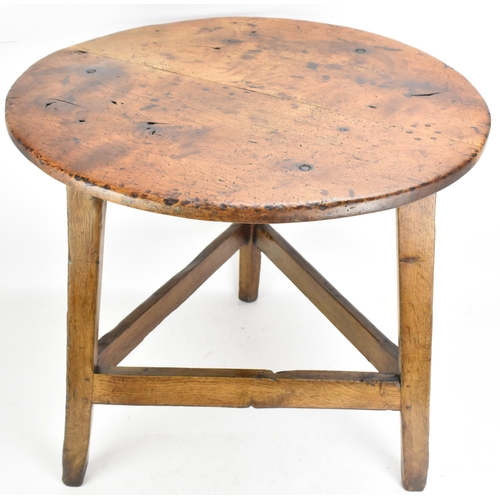 169 - An 18th century fruitwood topped vernacular cricket table, having a circular top, three splayed legs... 