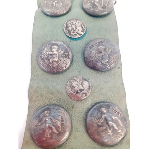 34 - A display of Circa 1900 French and English silver buttons, 17 in total, mounted on a green leather s... 