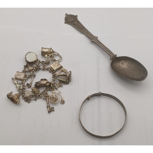 159 - Silver and white metal to include a tablespoon, bangle and charm bracelet having several charms to i... 