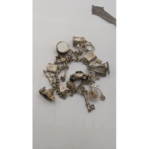 159 - Silver and white metal to include a tablespoon, bangle and charm bracelet having several charms to i... 