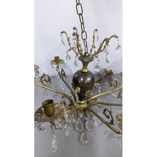 440 - A gilt metal eight-branch chandelier having scroll mounts, baluster columns and faceted cut glass dr... 