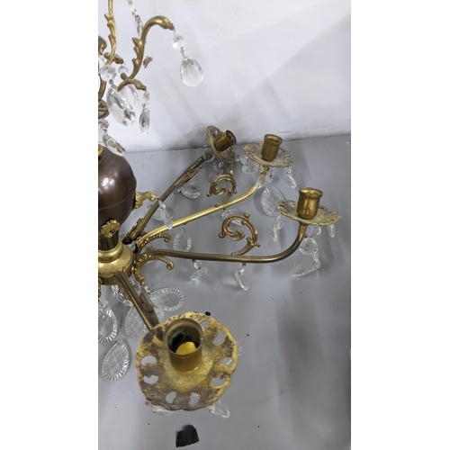 440 - A gilt metal eight-branch chandelier having scroll mounts, baluster columns and faceted cut glass dr... 