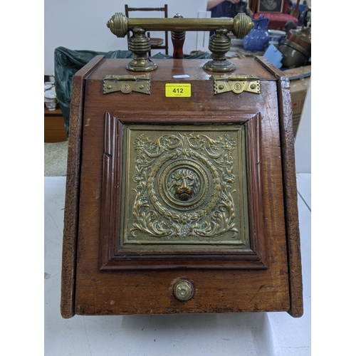 412 - A late Victorian oak coal scuttle with a brass handle, hinges, decorative plaque depicting a lions f... 