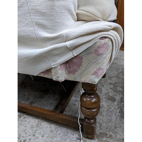 457 - An early to mid 20th century oak and upholstered wing back chair, floral fabric with cream over cove... 