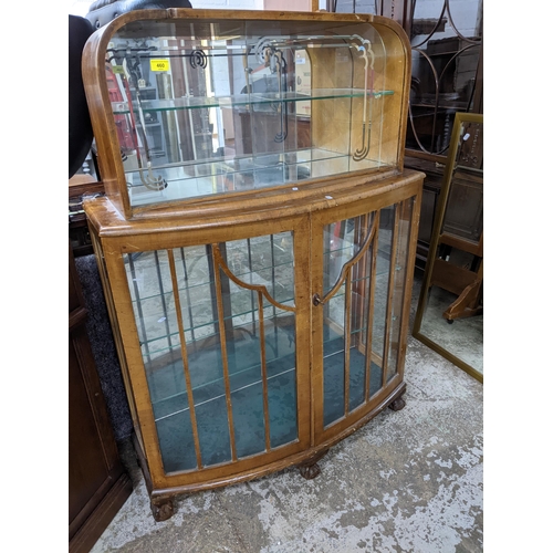 460 - An Art Deco walnut display/drinks cabinet, bow fronted, the top with mirrored glass behind a single ... 