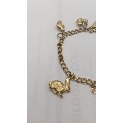 1 - A 
9ct gold charm bracelet with eight 9ct and yellow gold charms to include a lion, rabbit, penguin ... 