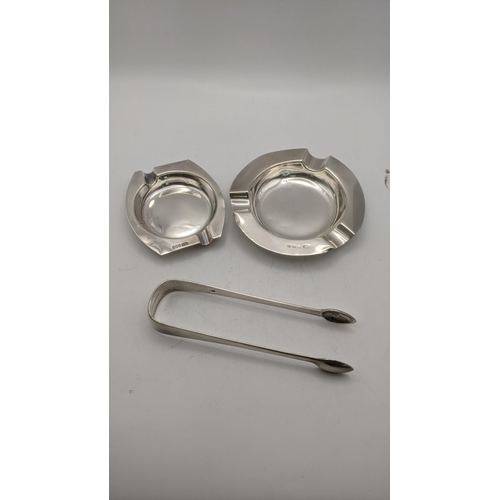 103 - Silver to include two ashtrays and a pair of sugar tongs, tongs hallmarked 1809, total weight 148.4g... 