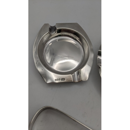 103 - Silver to include two ashtrays and a pair of sugar tongs, tongs hallmarked 1809, total weight 148.4g... 