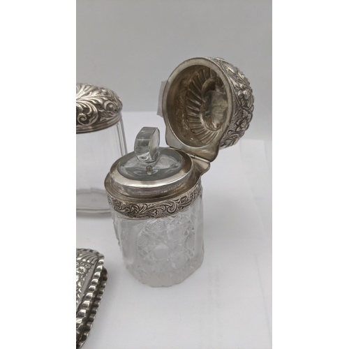 66 - Silver dressing table items to include three pots/jars, two having floral embossed lids, together wi... 