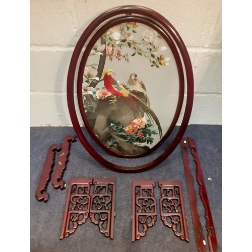 67 - An Oriental screen in oval form mounted on a red wooden frame with a silk embroidered picture amongs... 