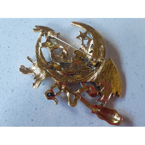 499 - A large gold tone, enamel effect and coloured crystal brooch in the form of a winged witch sat on a ... 