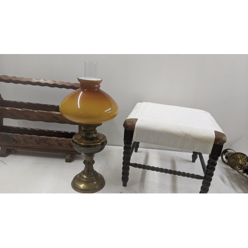 552 - A mid century dark wood magazine rack, together with bobbin turned stool and a brass and an oil lamp... 