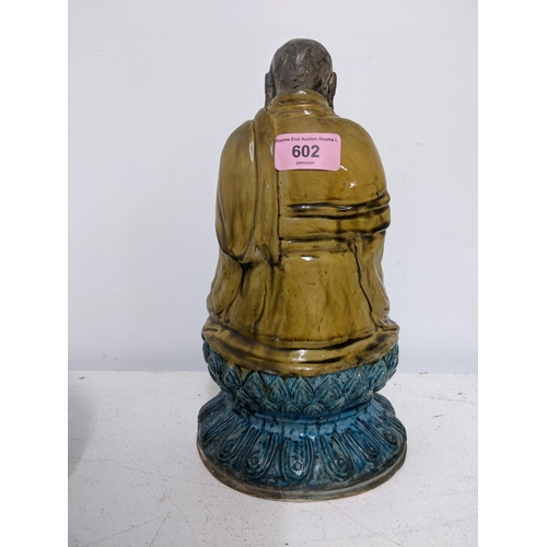 602 - THIS LOT HAS BEEN WITHDRAWN

 Chinese pottery figure of a Luohan, seated with hands clasps in a dark... 