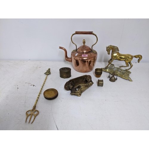 608 - A selection of brass and copper wares to include a door knocker in the form of a hand holding a ball... 