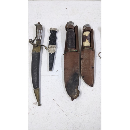 521 - A collection of knives and daggers to include a Scottish Skean Dhu dagger, two Bowie knives in leath... 