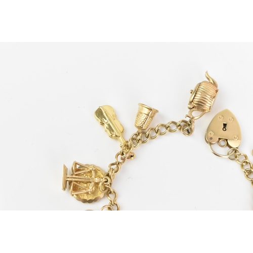 108 - A 9ct yellow gold curb link charm bracelet, with various 9ct gold charms including a thimble, teapot... 