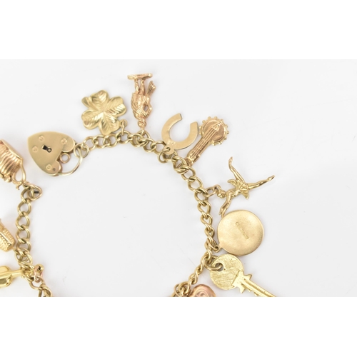 108 - A 9ct yellow gold curb link charm bracelet, with various 9ct gold charms including a thimble, teapot... 