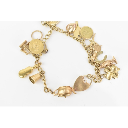 108 - A 9ct yellow gold curb link charm bracelet, with various 9ct gold charms including a thimble, teapot... 