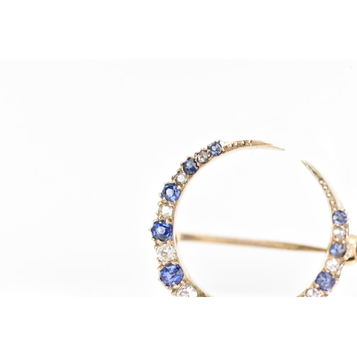 120 - A diamond and sapphire crescent brooch, set with eleven graduated sapphires, the largest 3mm x 2.6mm... 