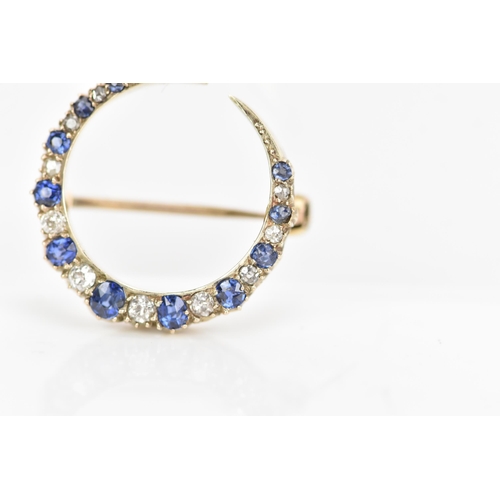 120 - A diamond and sapphire crescent brooch, set with eleven graduated sapphires, the largest 3mm x 2.6mm... 