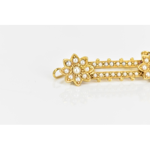 121 - A Victorian 18ct gold seed pearl brooch, having two flower heads united by two bars, each inset with... 