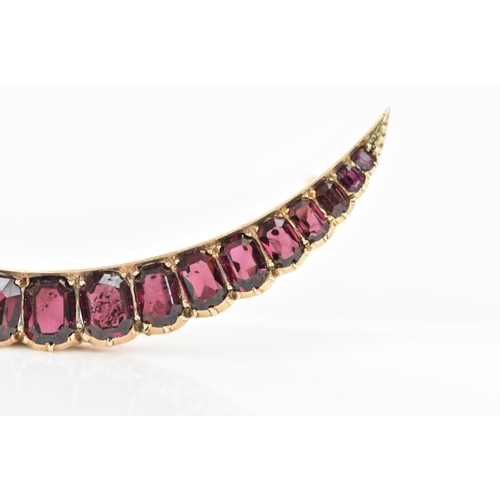 145 - An Edwardian yellow metal crescent brooch, inset with nineteen faceted cut graduating garnets, large... 