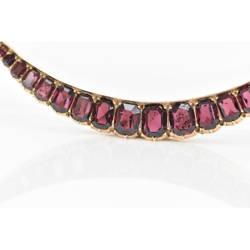 145 - An Edwardian yellow metal crescent brooch, inset with nineteen faceted cut graduating garnets, large... 