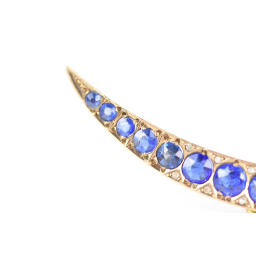 146 - An Edwardian 9ct gold crescent brooch, inset with fifteen blue coloured graduating stones and twelve... 