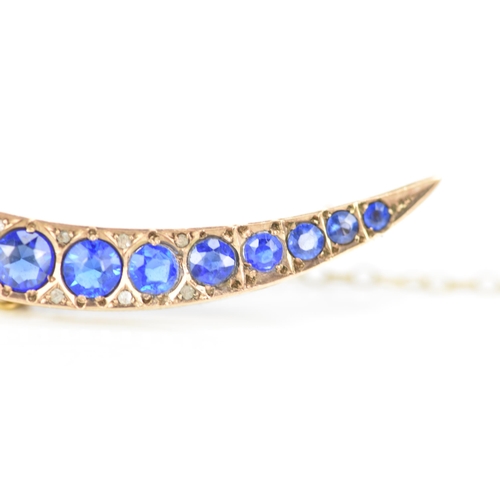 146 - An Edwardian 9ct gold crescent brooch, inset with fifteen blue coloured graduating stones and twelve... 