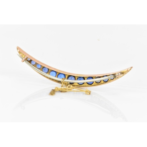 146 - An Edwardian 9ct gold crescent brooch, inset with fifteen blue coloured graduating stones and twelve... 