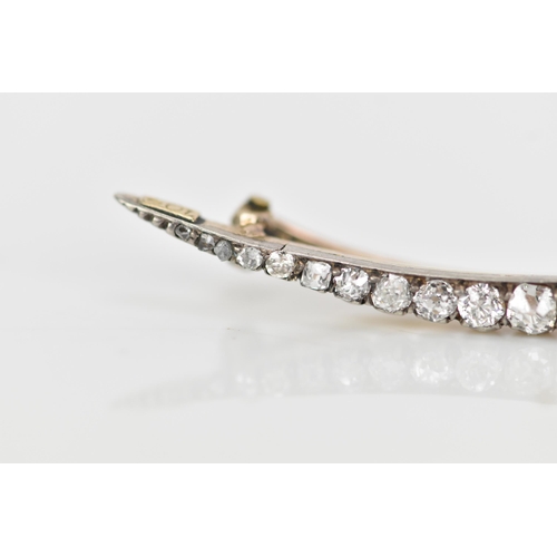 156 - A Victorian yellow and white metal crescent brooch, inset with old and rose cut graduating diamonds ... 