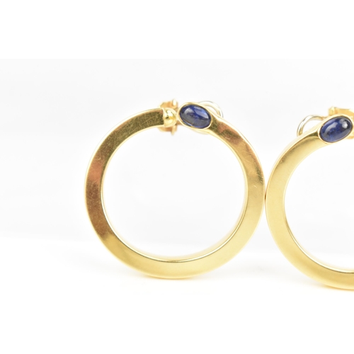 205 - A pair of 18ct yellow gold hoop earrings, each inset with a blue sapphire cabochon, stamped 750, 35.... 