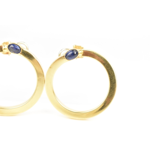 205 - A pair of 18ct yellow gold hoop earrings, each inset with a blue sapphire cabochon, stamped 750, 35.... 