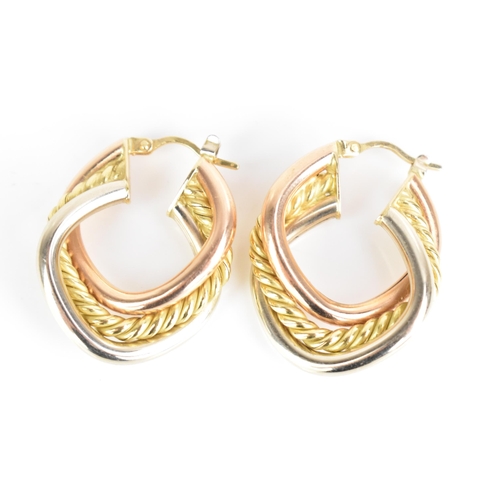 207 - A pair of 18ct tri-coloured gold hoop earrings, each having a central yellow gold rope twist entwine... 