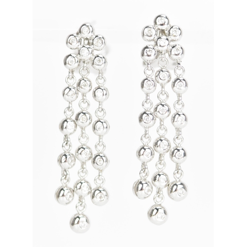 229 - A pair of 18ct white gold and diamond earrings, each composed of three articulated tassel drops and ... 