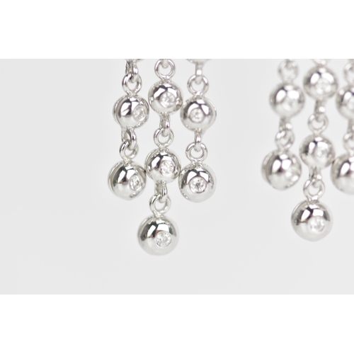 229 - A pair of 18ct white gold and diamond earrings, each composed of three articulated tassel drops and ... 