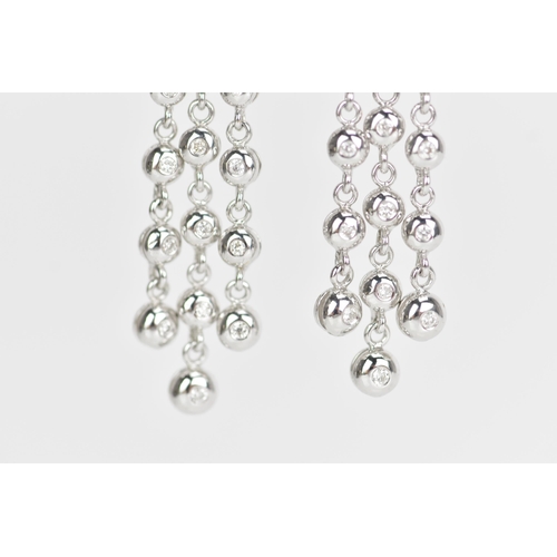 229 - A pair of 18ct white gold and diamond earrings, each composed of three articulated tassel drops and ... 