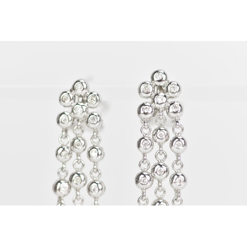 229 - A pair of 18ct white gold and diamond earrings, each composed of three articulated tassel drops and ... 