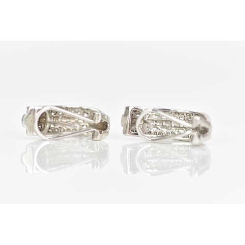 235 - A pair of 10ct white gold diamond earrings, each inset with a row of baguette cut diamonds surrounde... 