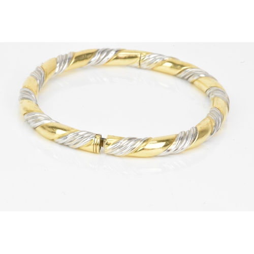 54 - An 18ct gold bi-coloured bangle, having a gadrooned design alternating in yellow and white gold, sta... 