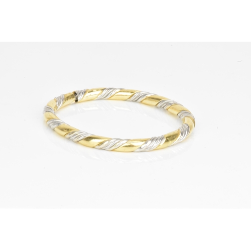 54 - An 18ct gold bi-coloured bangle, having a gadrooned design alternating in yellow and white gold, sta... 