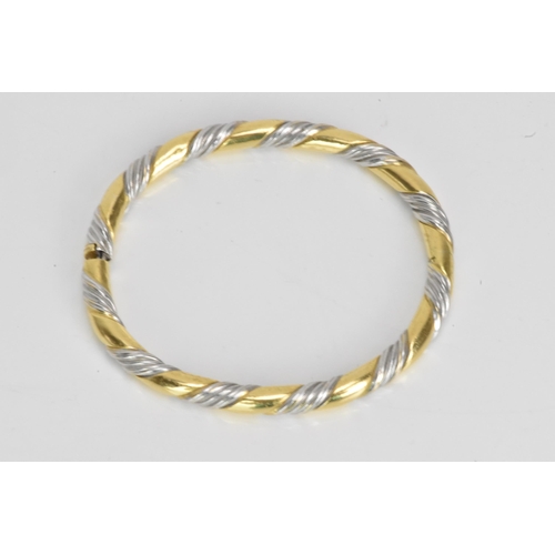 54 - An 18ct gold bi-coloured bangle, having a gadrooned design alternating in yellow and white gold, sta... 