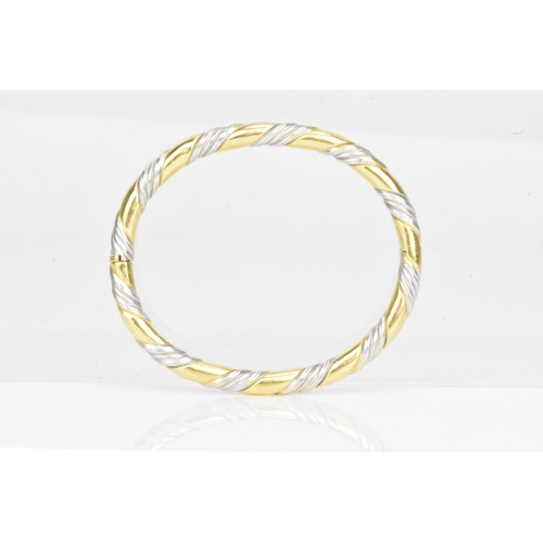 54 - An 18ct gold bi-coloured bangle, having a gadrooned design alternating in yellow and white gold, sta... 