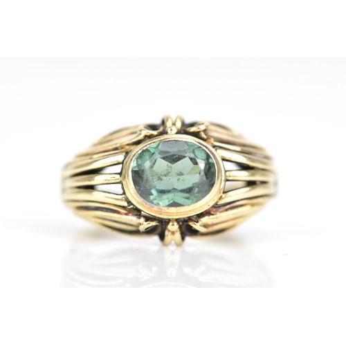 64 - A 14ct yellow gold and oval cut green tourmaline ring, 7.8mm x 6.3mm, set in a pierced scroll work s... 