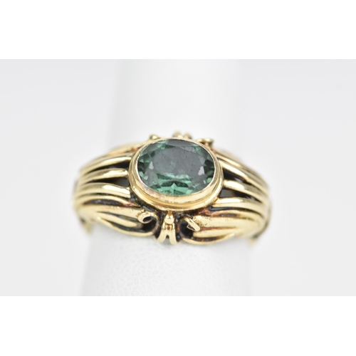 64 - A 14ct yellow gold and oval cut green tourmaline ring, 7.8mm x 6.3mm, set in a pierced scroll work s... 