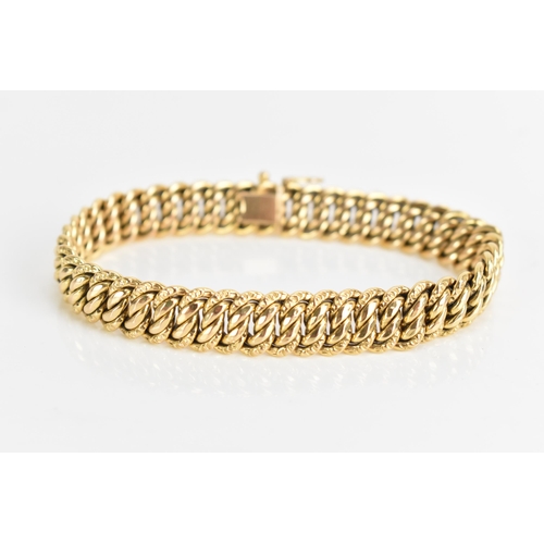 69 - A yellow gold chain link bracelet, tests at 18ct gold, having an open box clasp and with an interloc... 