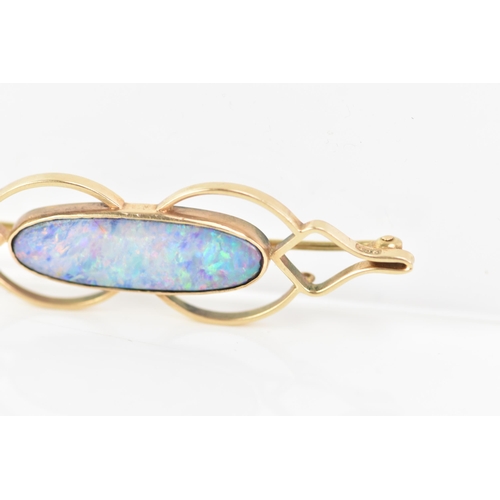 243 - A 9ct yellow gold and opal brooch, the oval opal 25.8mm x 7.7mm set in a pierced frame, stamped 9ct,... 