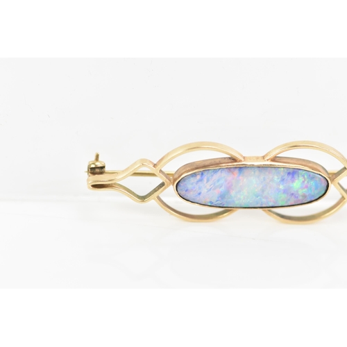 243 - A 9ct yellow gold and opal brooch, the oval opal 25.8mm x 7.7mm set in a pierced frame, stamped 9ct,... 